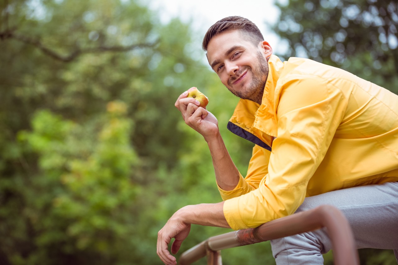 Fit man eating an apple in the countryside